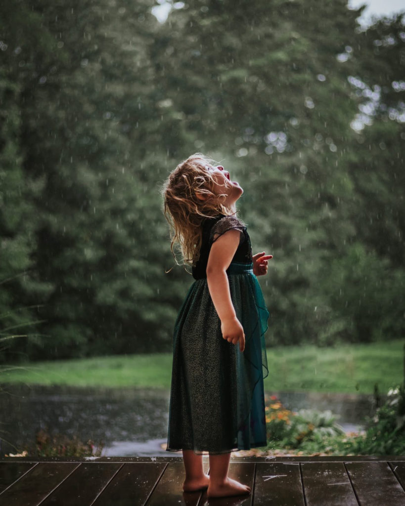 Child catching rain in mouth