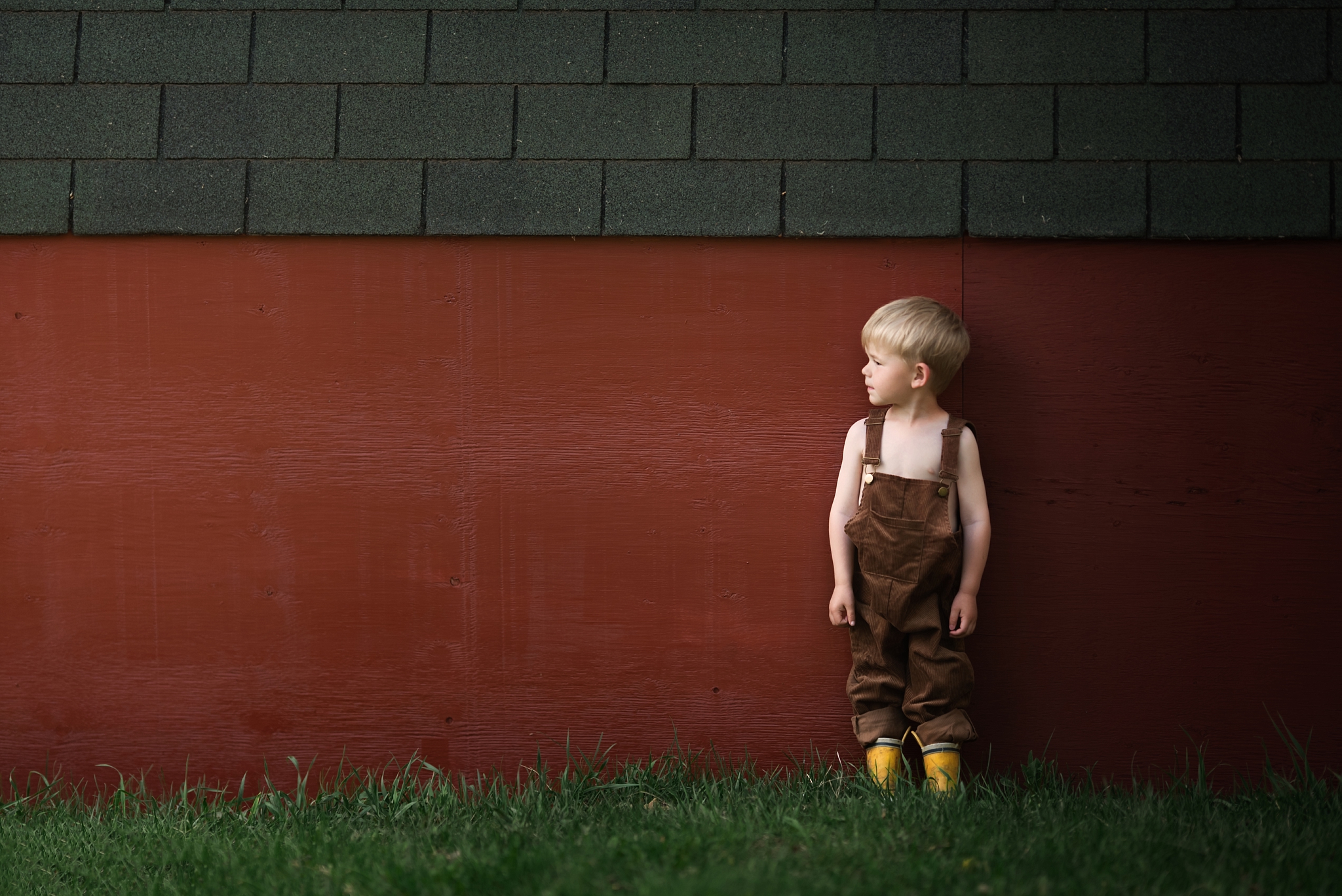 Little boy standing next to barn