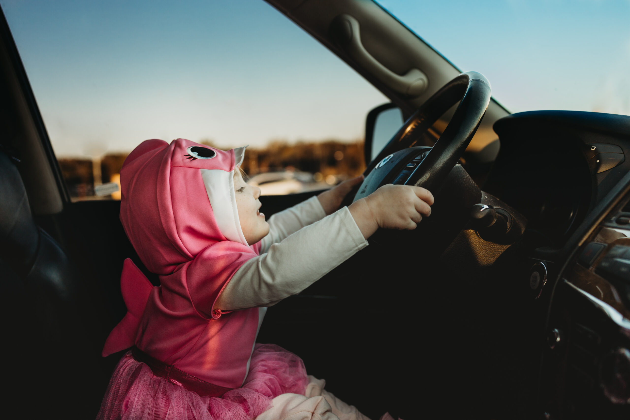 Little girl in the drivers seat of a parked car