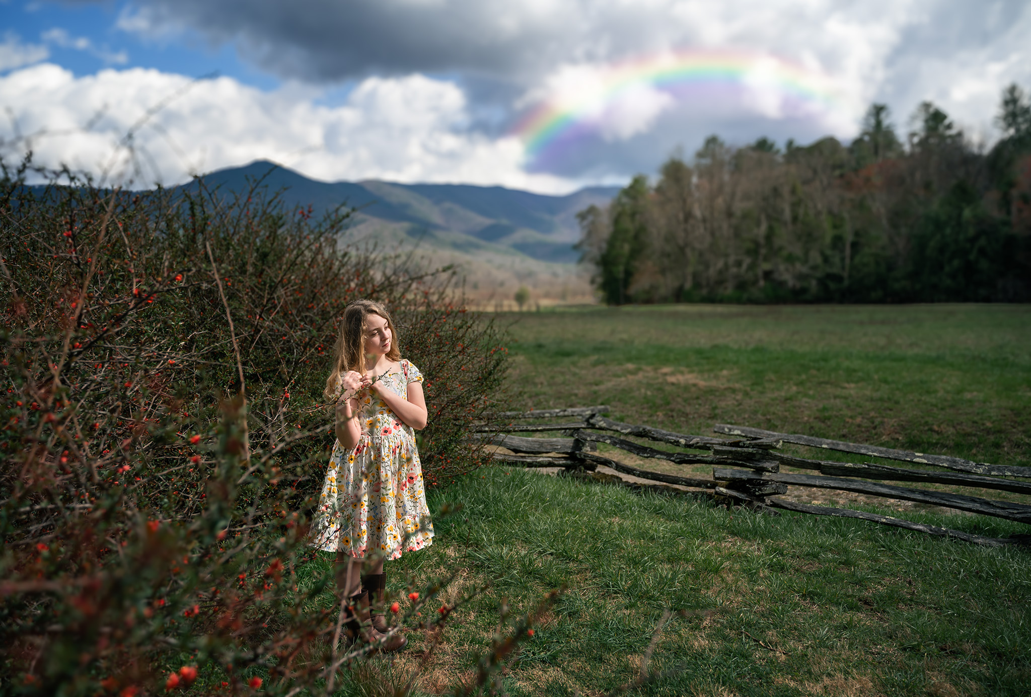 Girl standing in a field with a rainbow in the sky